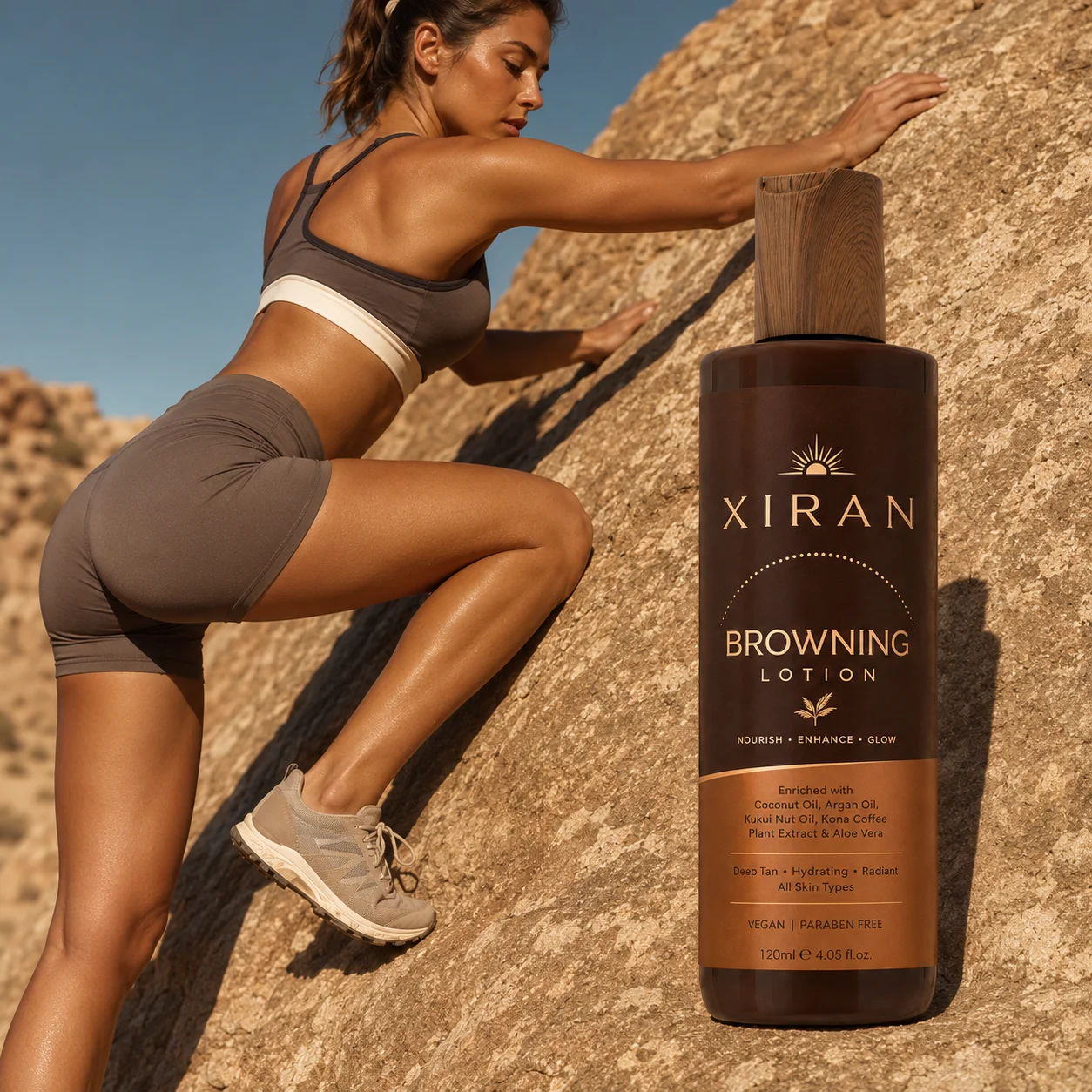A fitness model climbing a rocky surface wearing athletic attire, with a bottle of Xiran browning lotion prominently displayed in the foreground under natural sunlight.
